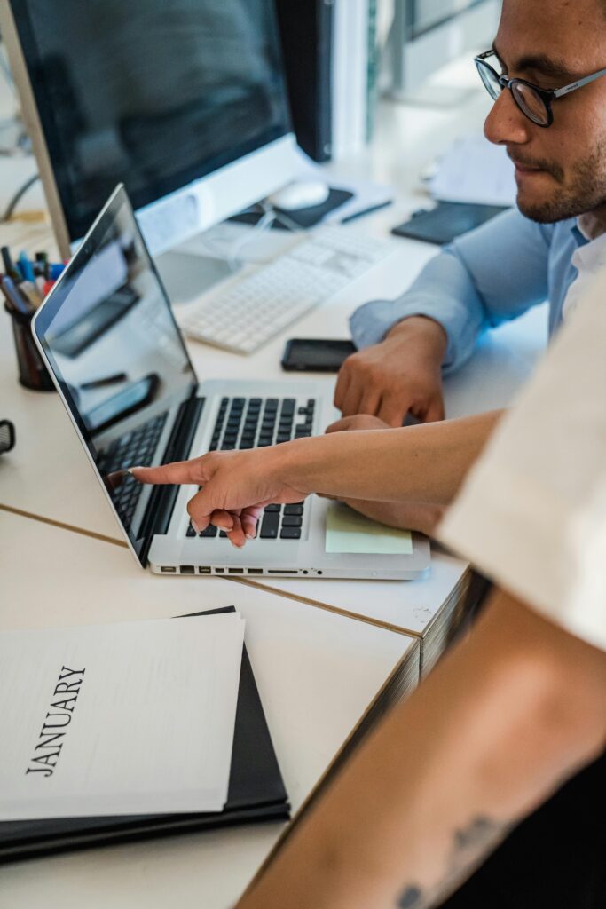 Team members working together on a laptop in a bright office setting, promoting teamwork and cooperation.